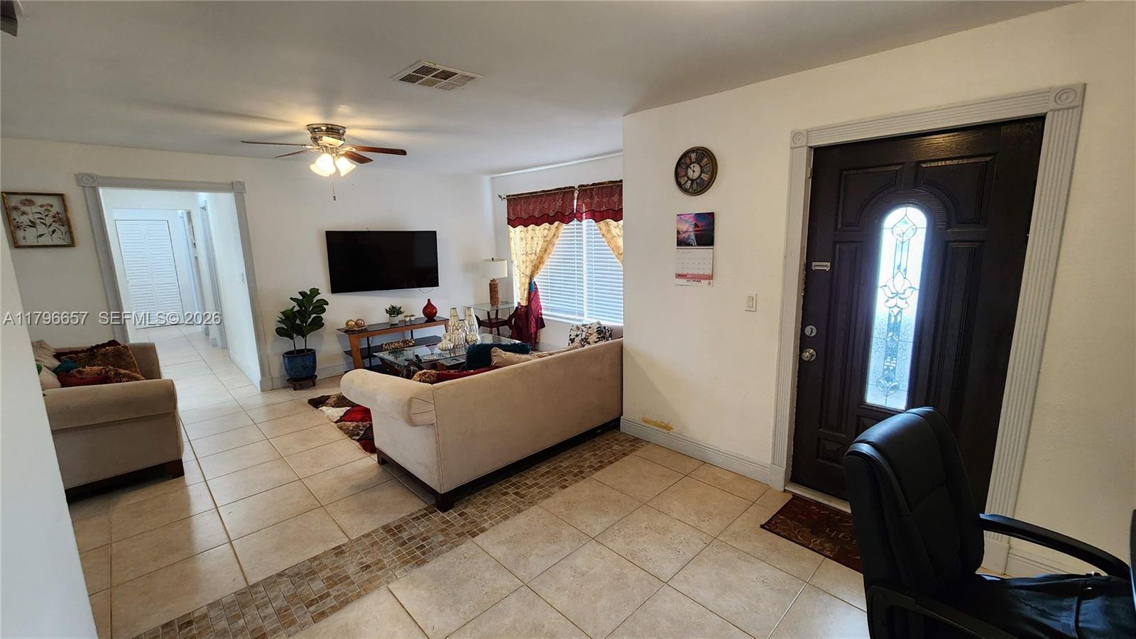 A living room features tile flooring, a beige sofa, a television, and a front door — 6881 Sheridan St, Hollywood FL 33024, HOLLYWOOD, FL