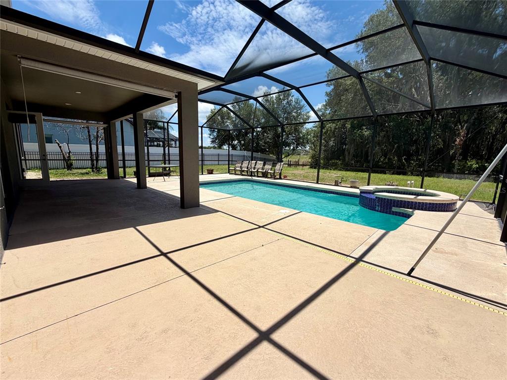 A rectangular swimming pool with an attached spa is enclosed by a screened lanai — 10531 MISTFLOWER LANE, TAMPA, FL