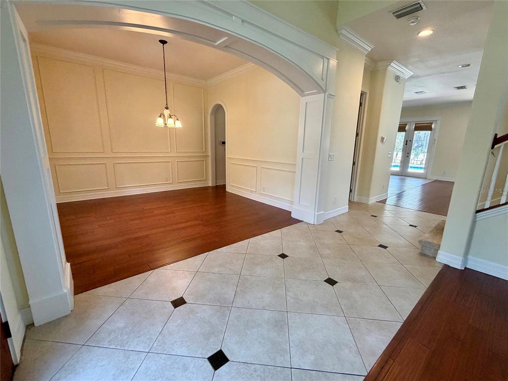 A dining room with wainscoting and wood floors sits beside a tiled entryway — 10531 MISTFLOWER LANE, TAMPA, FL