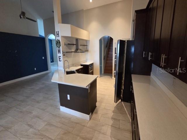 A modern kitchen features dark cabinets, white countertops, a central island, and light tile flooring — 4528 RIVER CLOSE BOULEVARD, VALRICO, FL