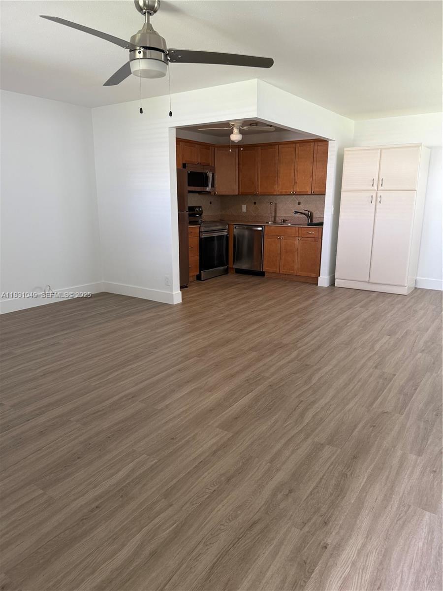 This room features wood-look flooring, a ceiling fan, and an open kitchen with wood cabinets — 67 Monaco B, Delray Beach FL 33446, DELRAY BEACH, FL
