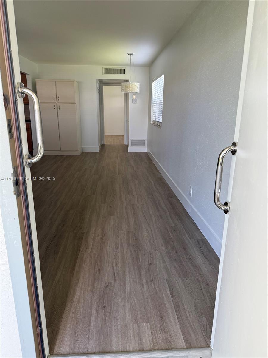 A view through a doorway into a room with wood-look flooring and a tall cabinet — 67 Monaco B, Delray Beach FL 33446, DELRAY BEACH, FL