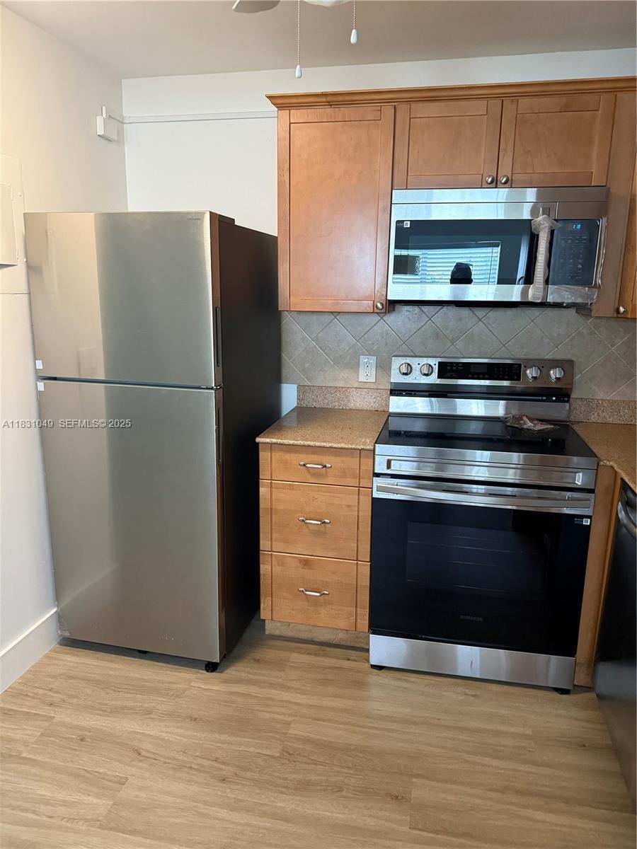 A kitchen features stainless steel appliances, wood cabinets, and a granite countertop — 67 Monaco B, Delray Beach FL 33446, DELRAY BEACH, FL