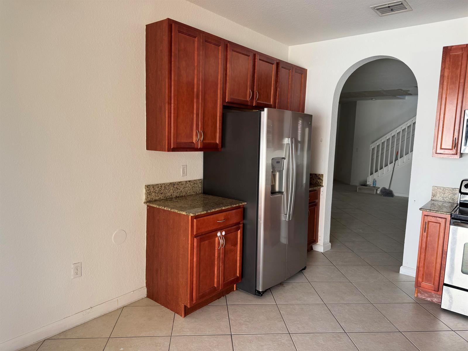 A kitchen features cherry wood cabinets, granite countertops, and a stainless steel refrigerator — 3977 NE 11th Drive, Homestead FL 33033, HOMESTEAD, FL