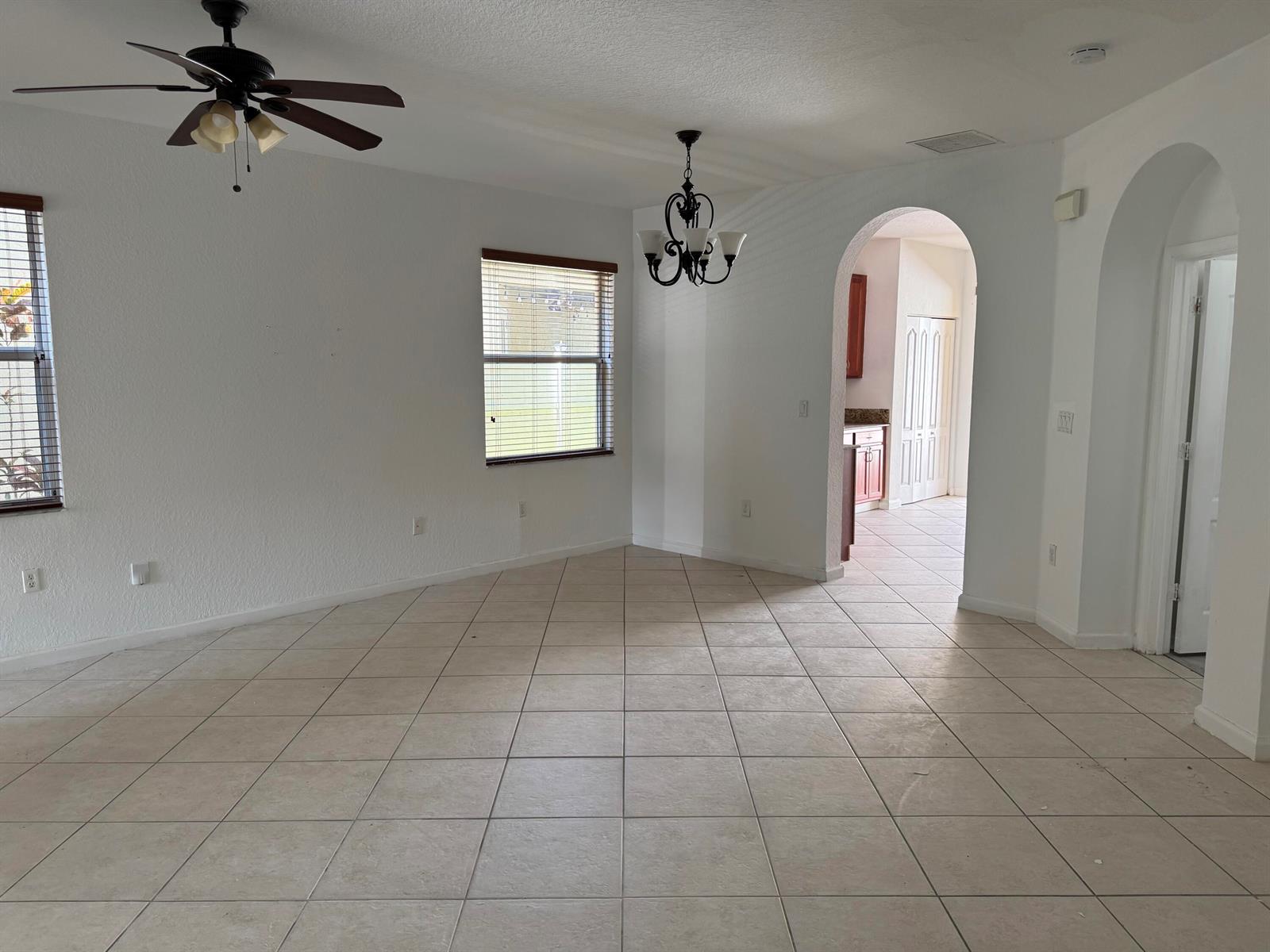 An empty room with white walls, tile flooring, a ceiling fan, and an arched doorway — 3977 NE 11th Drive, Homestead FL 33033, HOMESTEAD, FL