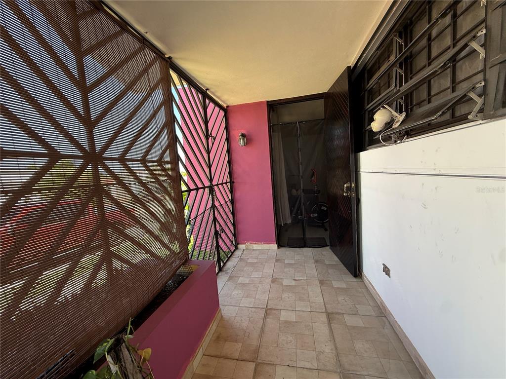 A covered balcony features tiled flooring, a pink wall, and a decorative metal privacy screen — SR 659 Villas del Capitan SOLANDRA ST UNIT AA-12, ARECIBO, PR