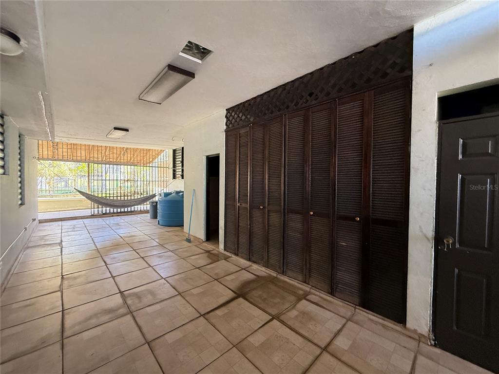 A covered patio features tiled flooring, a large wall of wooden louvered doors, and a hammock — SR 659 Villas del Capitan SOLANDRA ST UNIT AA-12, ARECIBO, PR