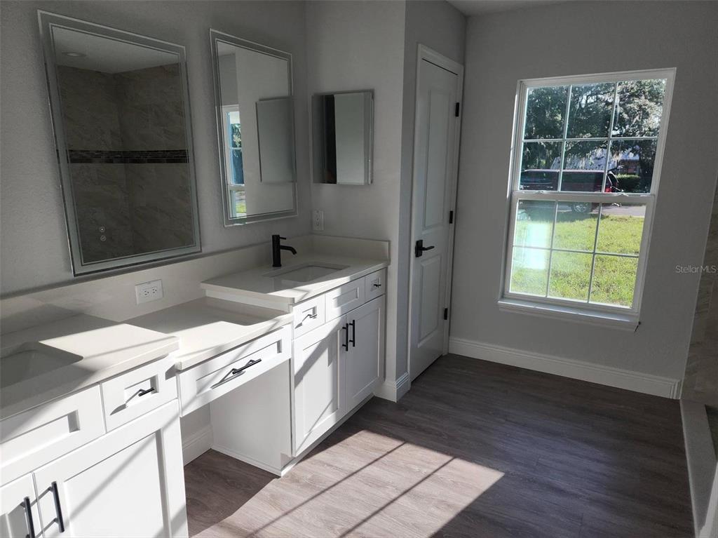 A bathroom features a double vanity with white cabinets, quartz countertops, and two wall mirrors — 1111 DAGMAR AVENUE, SPRING HILL, FL