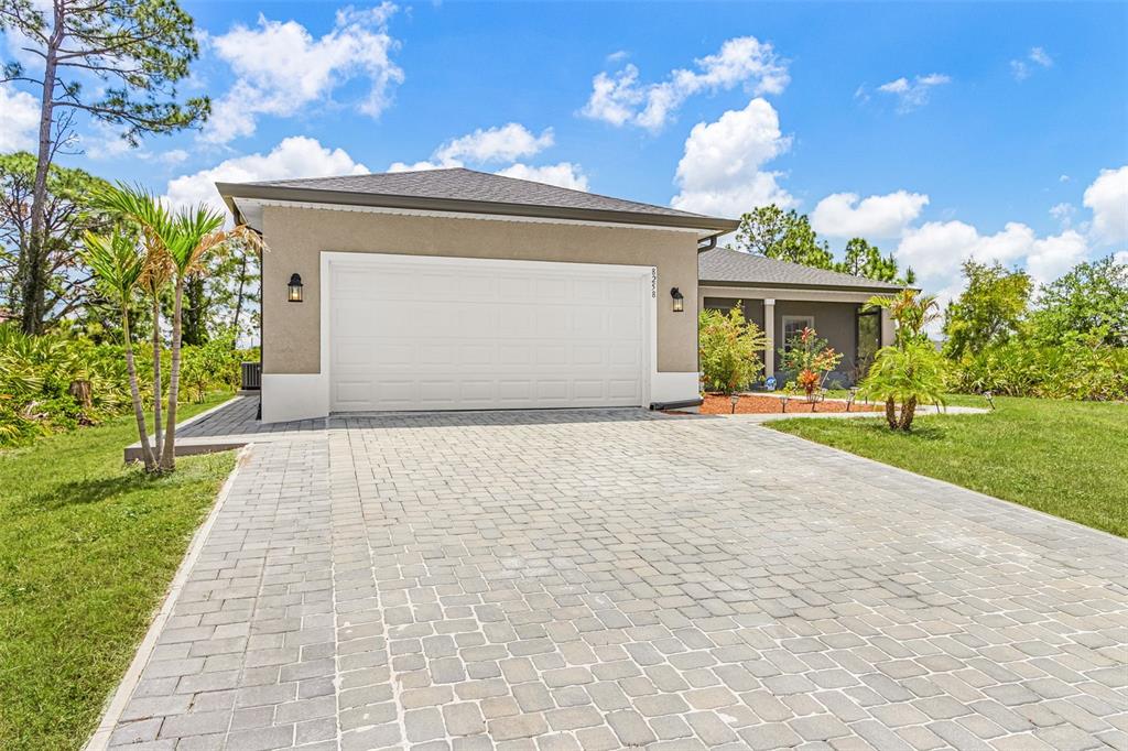 A single-story house with a paved driveway, a two-car garage, and a grassy front yard — 8258 DIMSTEAD STREET, PORT CHARLOTTE, FL