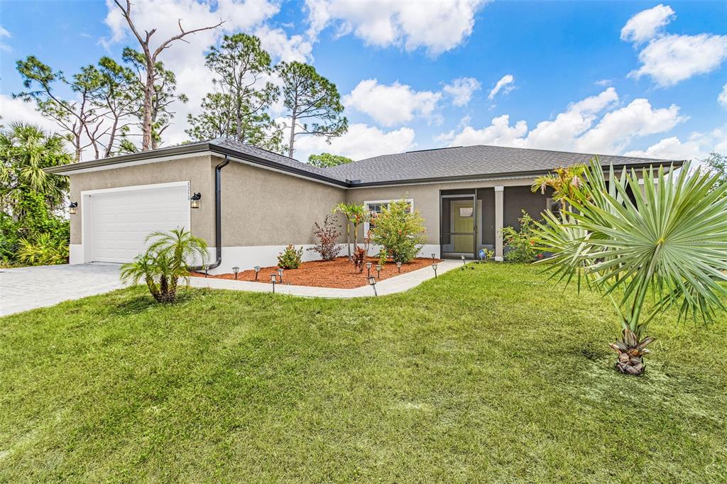 A paved driveway leads to the two-car garage of a single-story house with tan stucco — 8258 DIMSTEAD STREET, PORT CHARLOTTE, FL