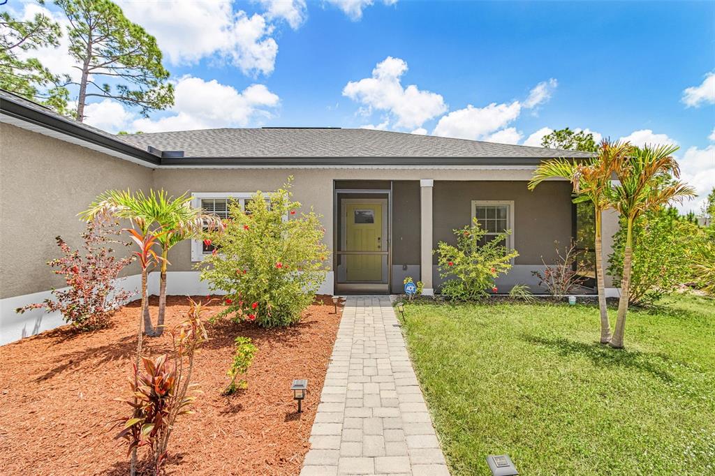 A single-story house with a beige stucco exterior, a two-car garage, and a front lawn — 8258 DIMSTEAD STREET, PORT CHARLOTTE, FL
