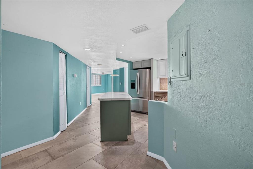 A kitchen with a central island, stainless steel refrigerator, and light blue walls — 935 N HALIFAX AVENUE UNIT 406, DAYTONA BEACH, FL