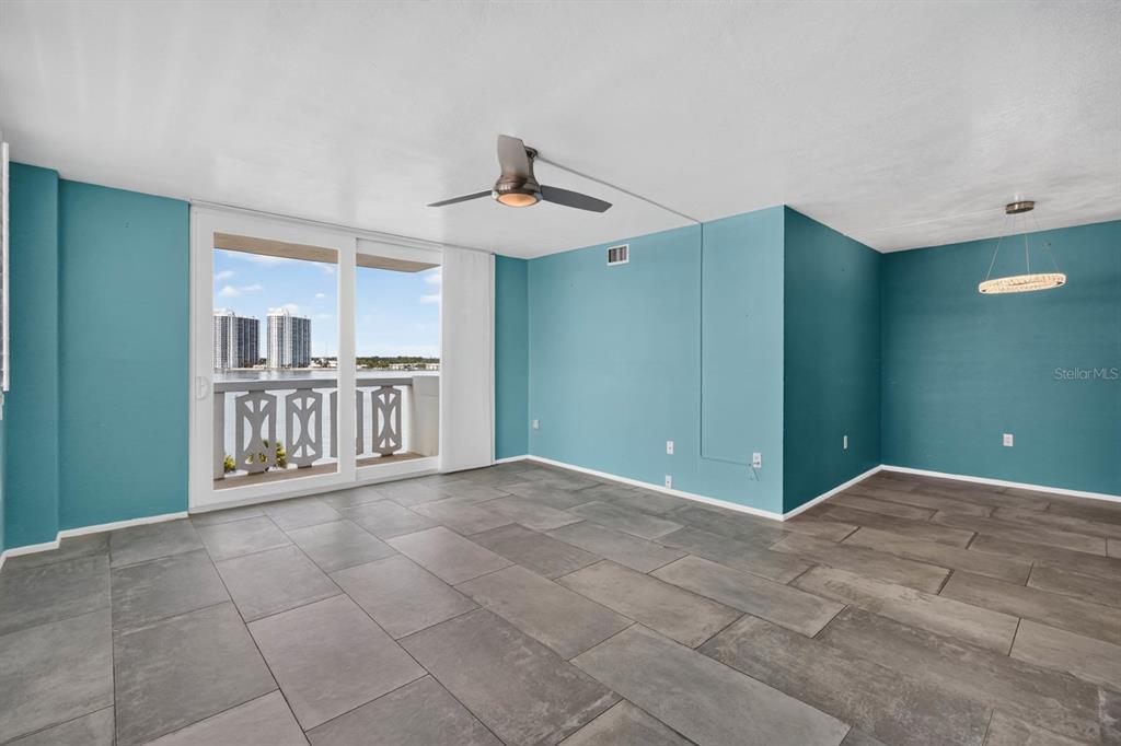 An empty room with teal walls, gray tile flooring, a ceiling fan, and a balcony — 935 N HALIFAX AVENUE UNIT 406, DAYTONA BEACH, FL