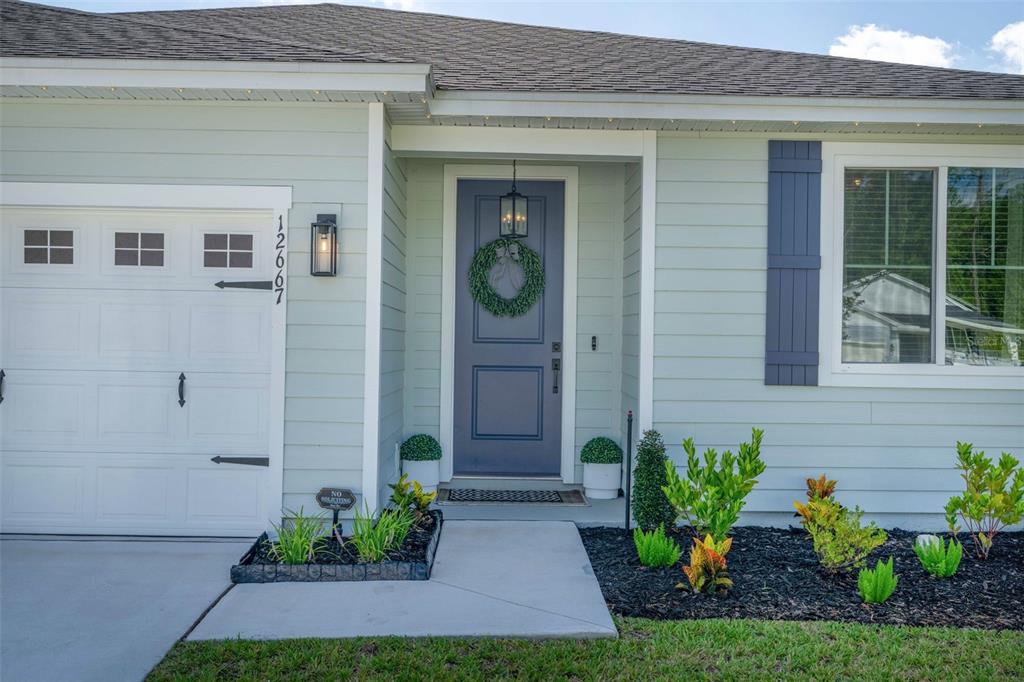 The exterior of a house features light green siding, a blue front door, and a garage — 12667 SENBAY COURT, JACKSONVILLE, FL