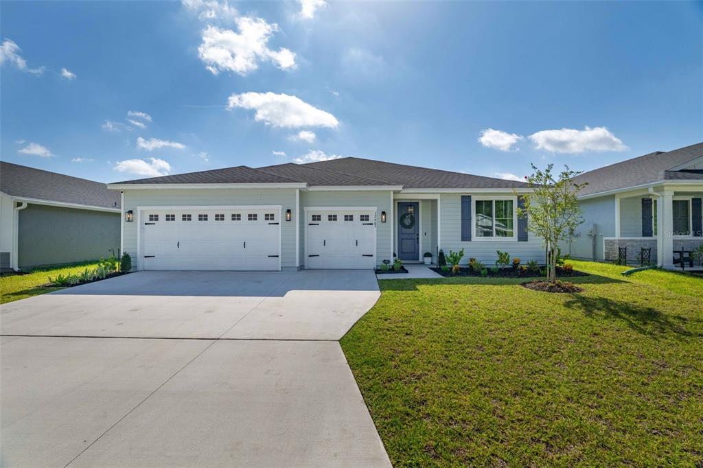 A single-story house with light blue siding, a three-car garage, and a concrete driveway — 12667 SENBAY COURT, JACKSONVILLE, FL