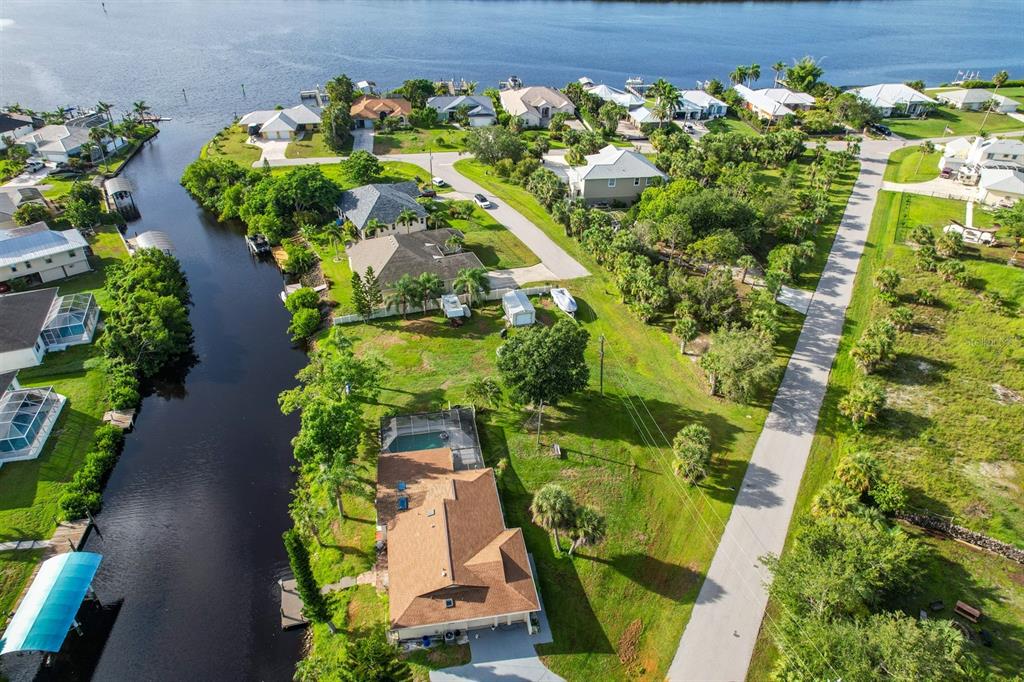 An aerial view shows a waterfront house with a pool along a canal and road — 3456 HIGHLANDS ROAD, PUNTA GORDA, FL
