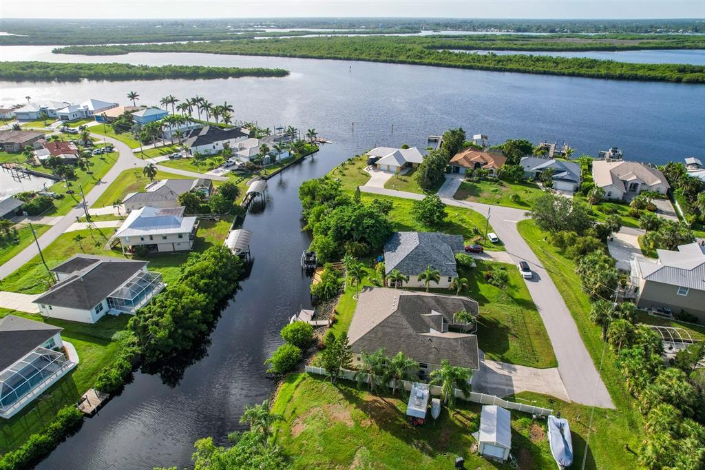 An aerial view shows waterfront homes along a canal leading to a larger body of water — 3456 HIGHLANDS ROAD, PUNTA GORDA, FL