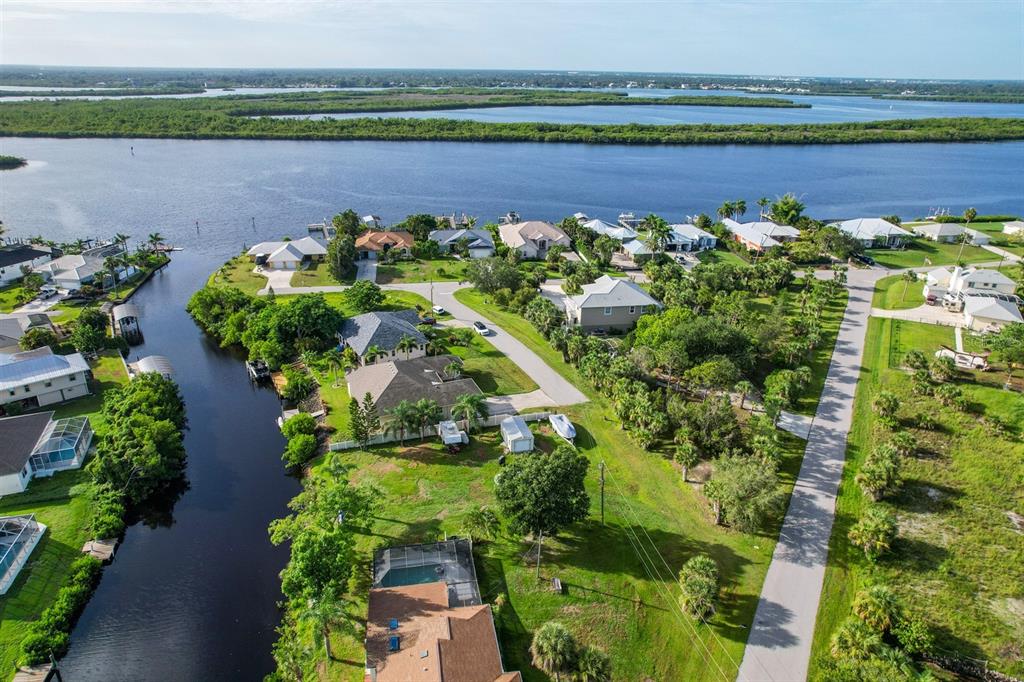 An aerial view shows waterfront houses along a canal leading to a large body of water — 3456 HIGHLANDS ROAD, PUNTA GORDA, FL