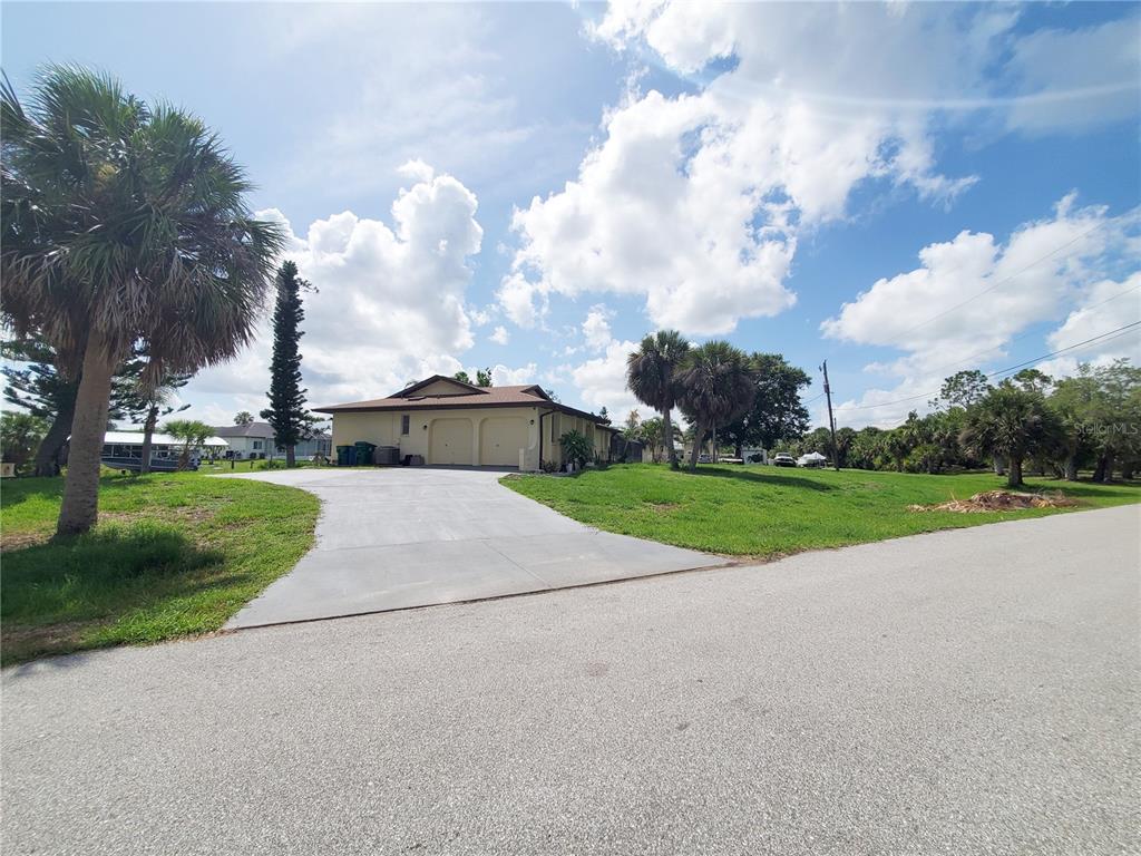 A single-story house with a two-car garage and a concrete driveway under a blue sky — 3456 HIGHLANDS ROAD, PUNTA GORDA, FL