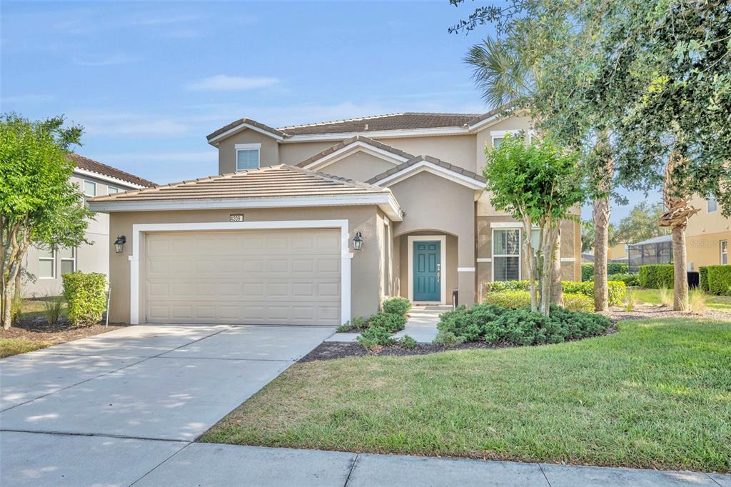 A two-story suburban house with a tan stucco exterior, a two-car garage, and a teal door — 4209 OAKVIEW DRIVE, DAVENPORT, FL