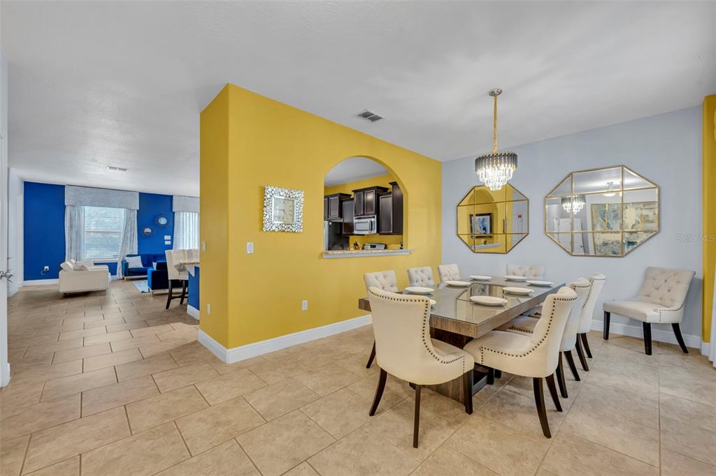 A dining room with a glass table and yellow wall connects to a blue living area — 4209 OAKVIEW DRIVE, DAVENPORT, FL