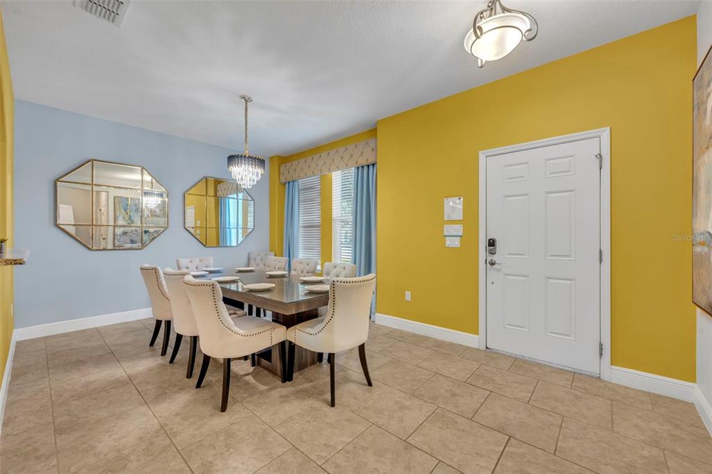 A dining room with a glass table, upholstered chairs, light blue walls, and yellow accents — 4209 OAKVIEW DRIVE, DAVENPORT, FL