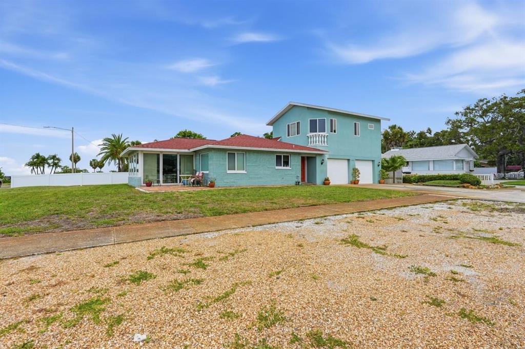 A two-story light blue house with a red roof stands behind a gravel driveway — 1963 EDGEWATER DRIVE, CLEARWATER, FL