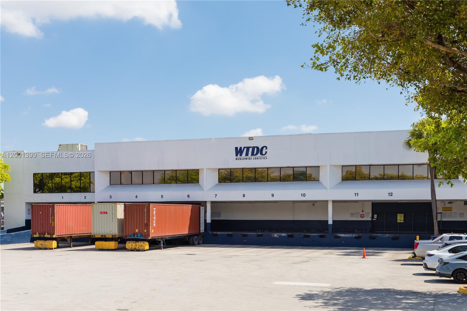 A commercial warehouse building features multiple loading docks with shipping containers parked in front — 2801 NW 74 AV # S07, Miami FL 33122, MIAMI, FL