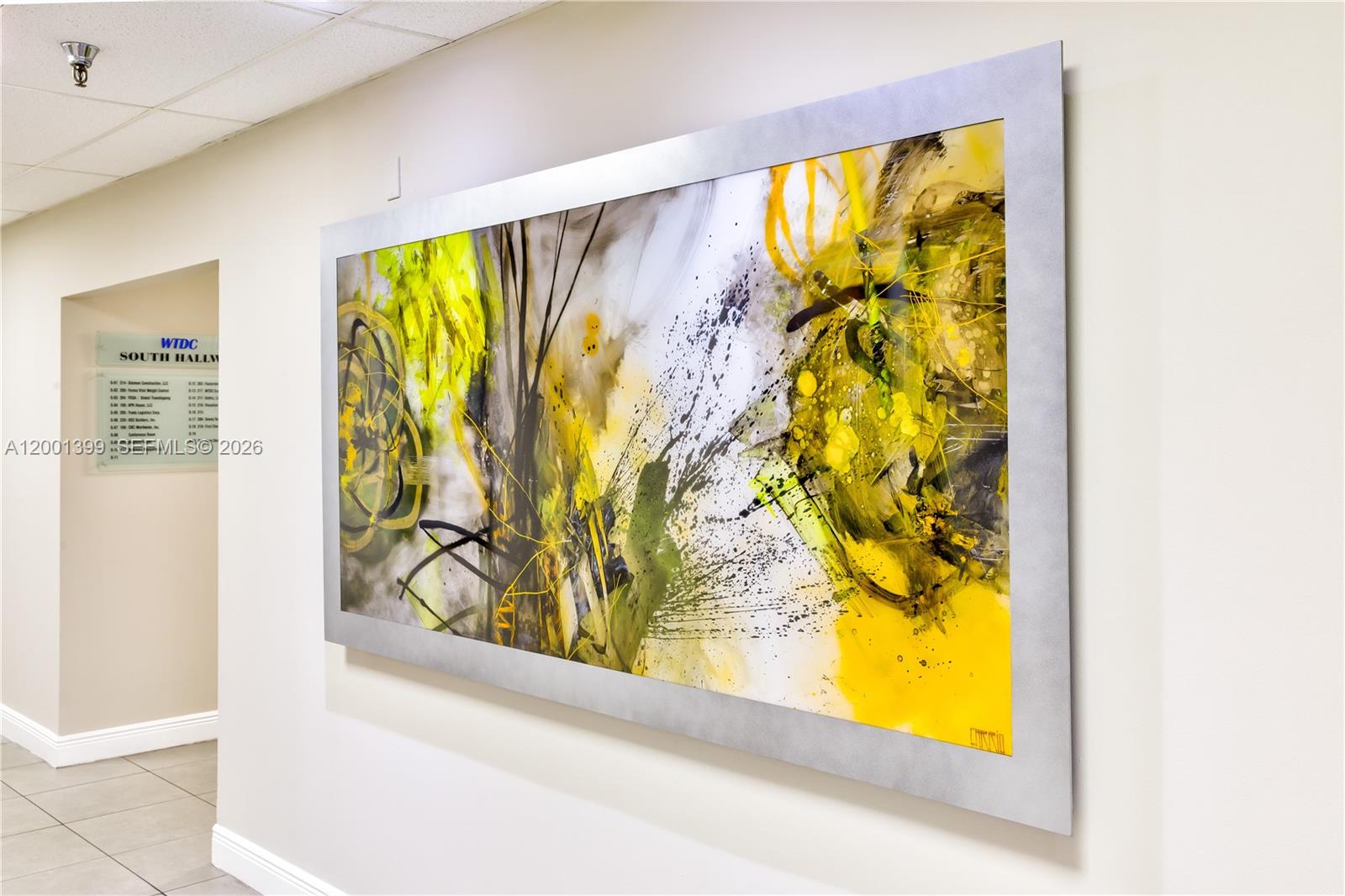 A large abstract painting with yellow and black accents hangs on a hallway wall — 2801 NW 74 AV # S07, Miami FL 33122, MIAMI, FL
