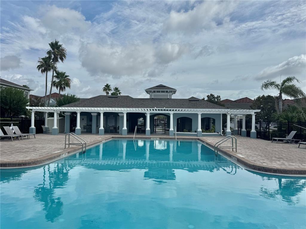 A swimming pool sits in front of a community clubhouse with a covered patio — 3141 WINDLESHORE WAY, SANFORD, FL