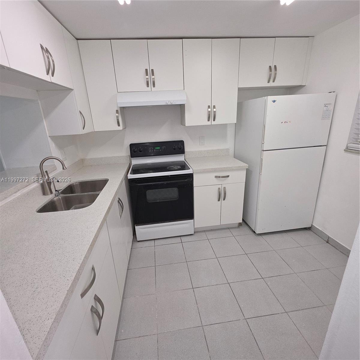 A kitchen features white cabinets, light countertops, a black stove, and a white refrigerator — 19771 SW 114th Ave # 129, Miami FL 33157, MIAMI, FL
