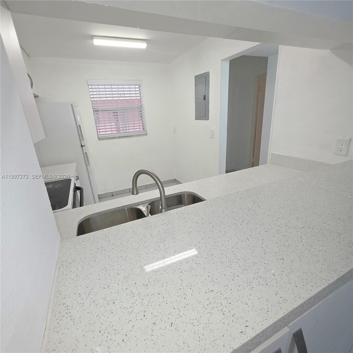 A kitchen features a white quartz countertop, a stainless steel sink, and white appliances — 19771 SW 114th Ave # 129, Miami FL 33157, MIAMI, FL