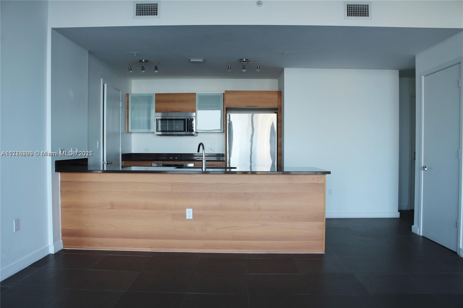 A modern kitchen features wood cabinets, stainless steel appliances, and a dark countertop island — 3301 NE 1 AV # H2904, Miami FL 33137, MIAMI, FL