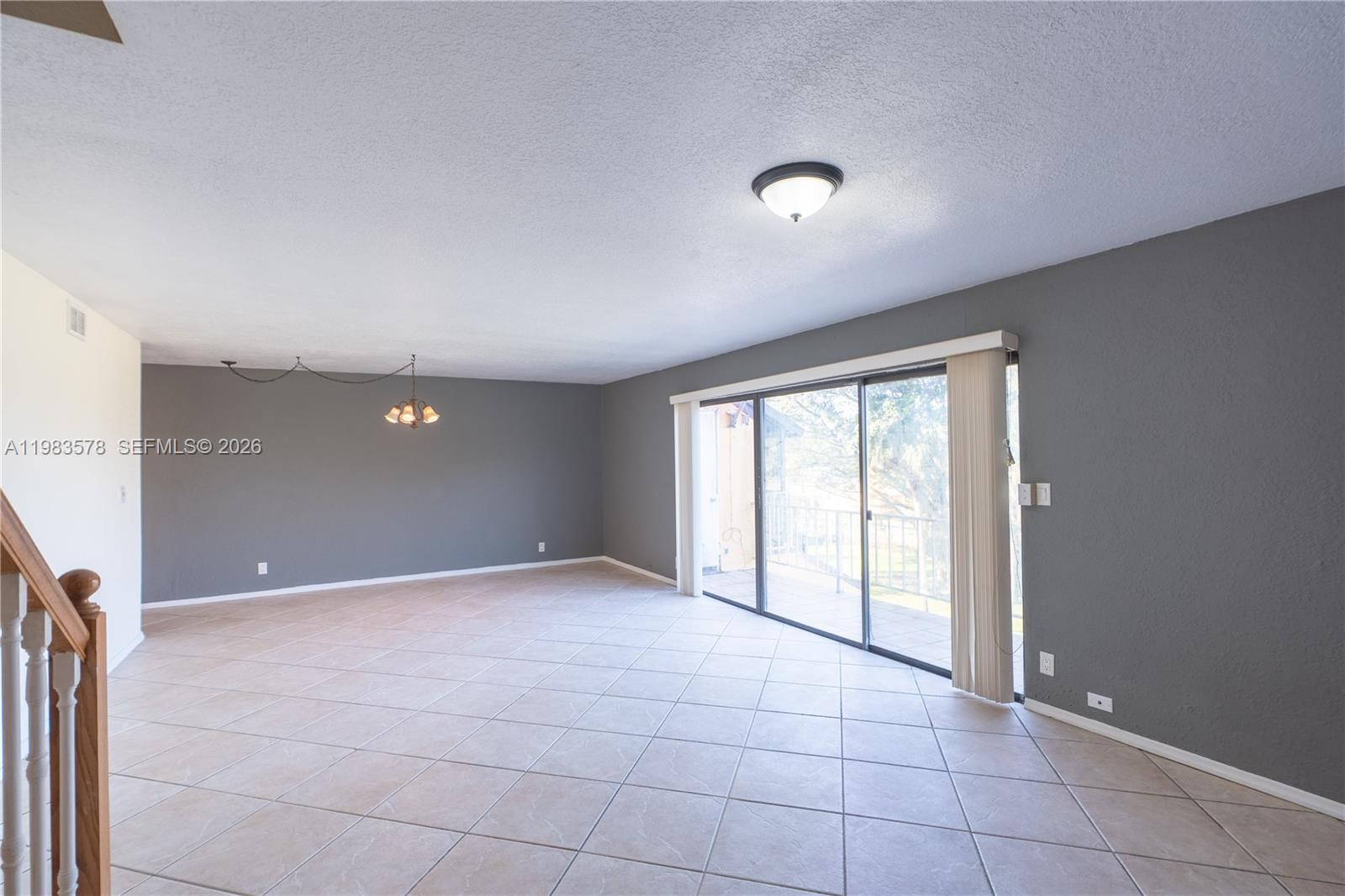 An empty living room features gray walls, beige tile flooring, and a sliding glass door — 430 Commodore Dr # 314, Plantation FL 33325, PLANTATION, FL