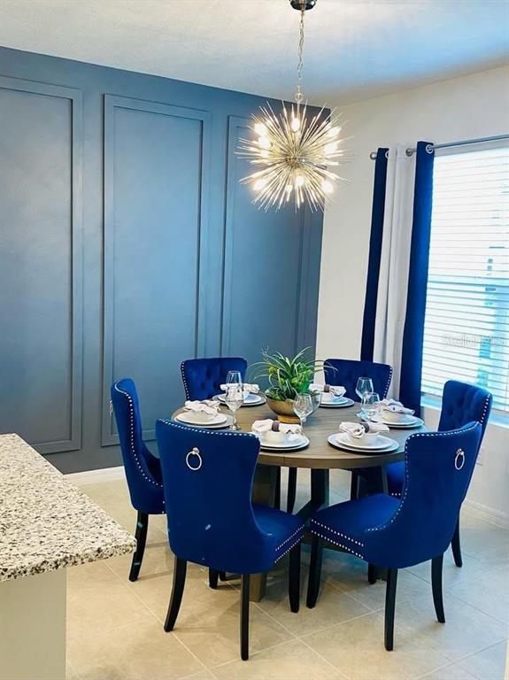 A dining room features a round wooden table, blue upholstered chairs, and a starburst chandelier — 2183 COPPER BELL PLACE, KISSIMMEE, FL