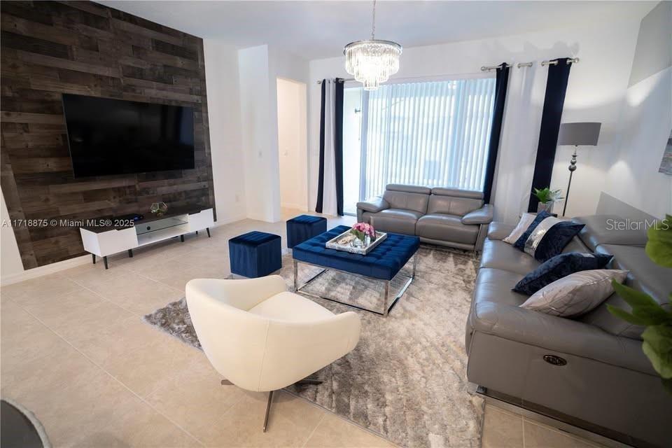 A living room features a wood-paneled accent wall, grey leather sofas, and a blue ottoman — 2183 COPPER BELL PLACE, KISSIMMEE, FL