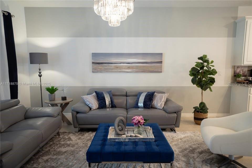 A living room features a grey sofa, a blue tufted ottoman, and a crystal chandelier — 2183 COPPER BELL PLACE, KISSIMMEE, FL
