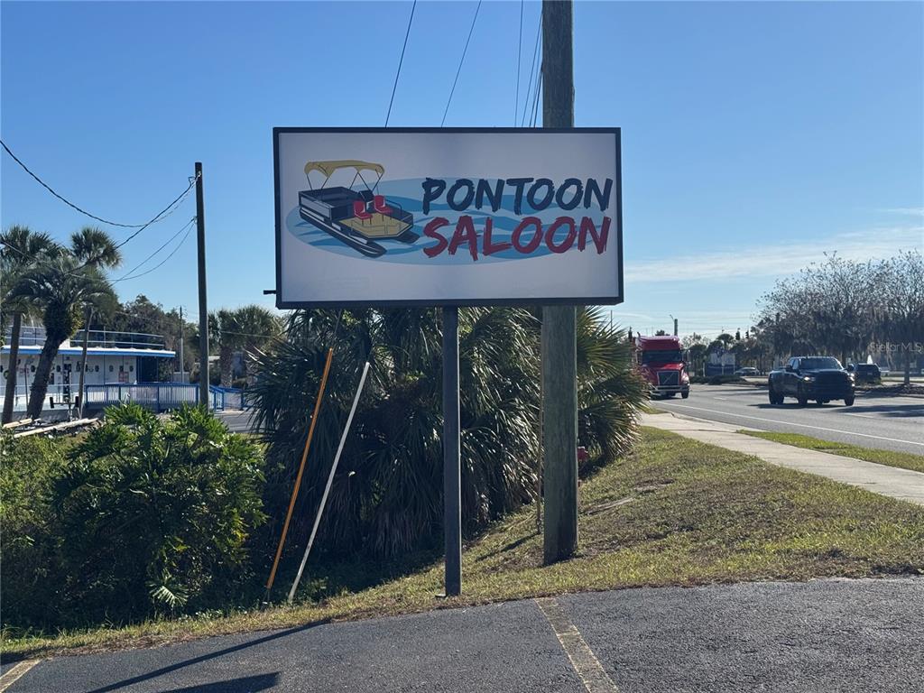 A sign for the Pontoon Saloon stands near a road with a truck and car — 1050 W BURLEIGH BOULEVARD, TAVARES, FL