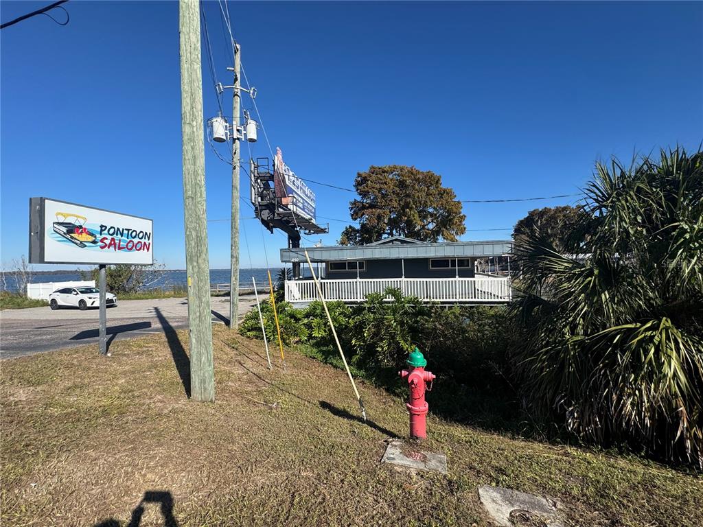A red fire hydrant stands in front of a building labeled Pontoon Saloon — 1050 W BURLEIGH BOULEVARD, TAVARES, FL