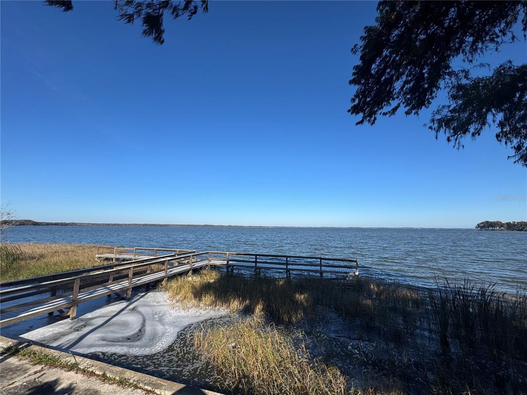 A wooden dock extends into a large lake under a clear blue sky — 1050 W BURLEIGH BOULEVARD, TAVARES, FL