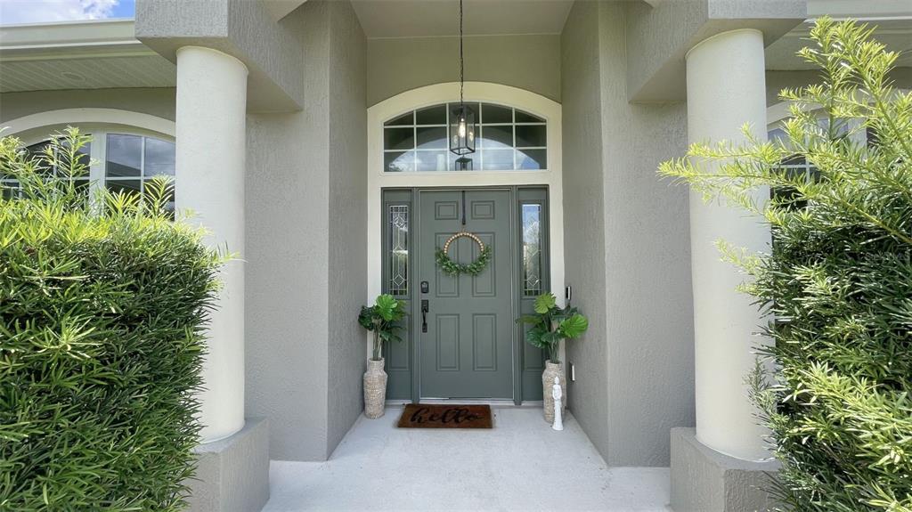 A green front door with a wreath sits between two columns under a covered entryway — 11321 OSWALT ROAD, CLERMONT, FL
