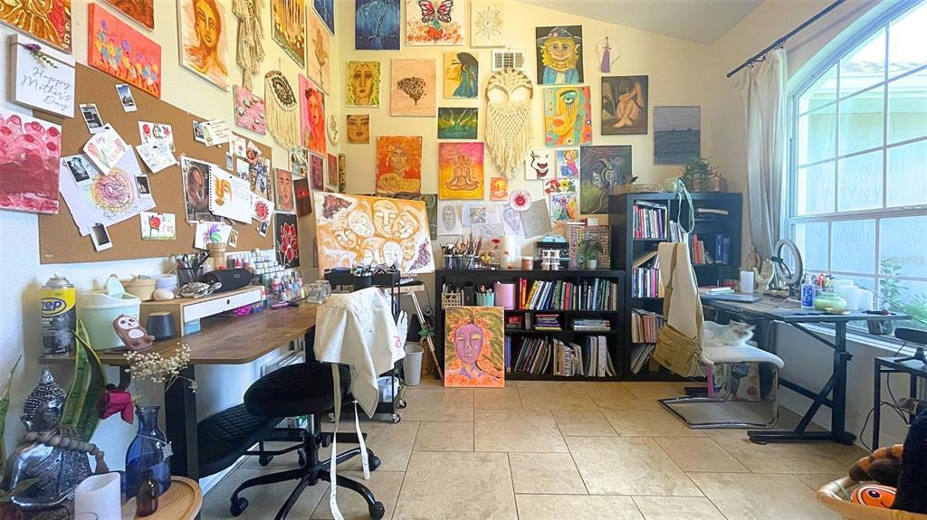 A home art studio features a desk, bookshelves, and numerous paintings displayed on the walls — 11321 OSWALT ROAD, CLERMONT, FL