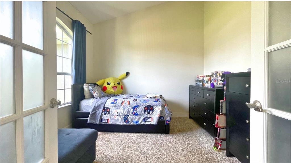 A bedroom features a bed with a Pikachu plush, a black dresser, and carpeted flooring — 11321 OSWALT ROAD, CLERMONT, FL
