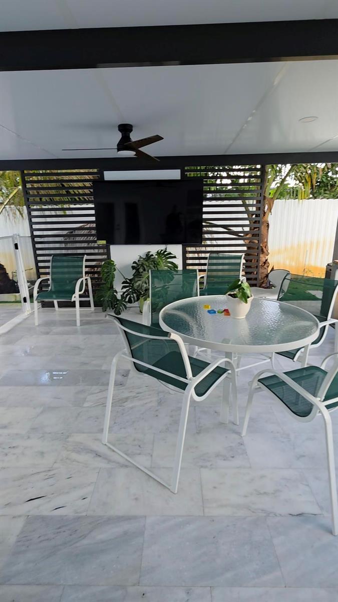 A concrete driveway leads to a white house with a carport and palm trees — 1902 Baythorne Road, West Palm Beach FL 33415, WEST PALM BEACH, FL