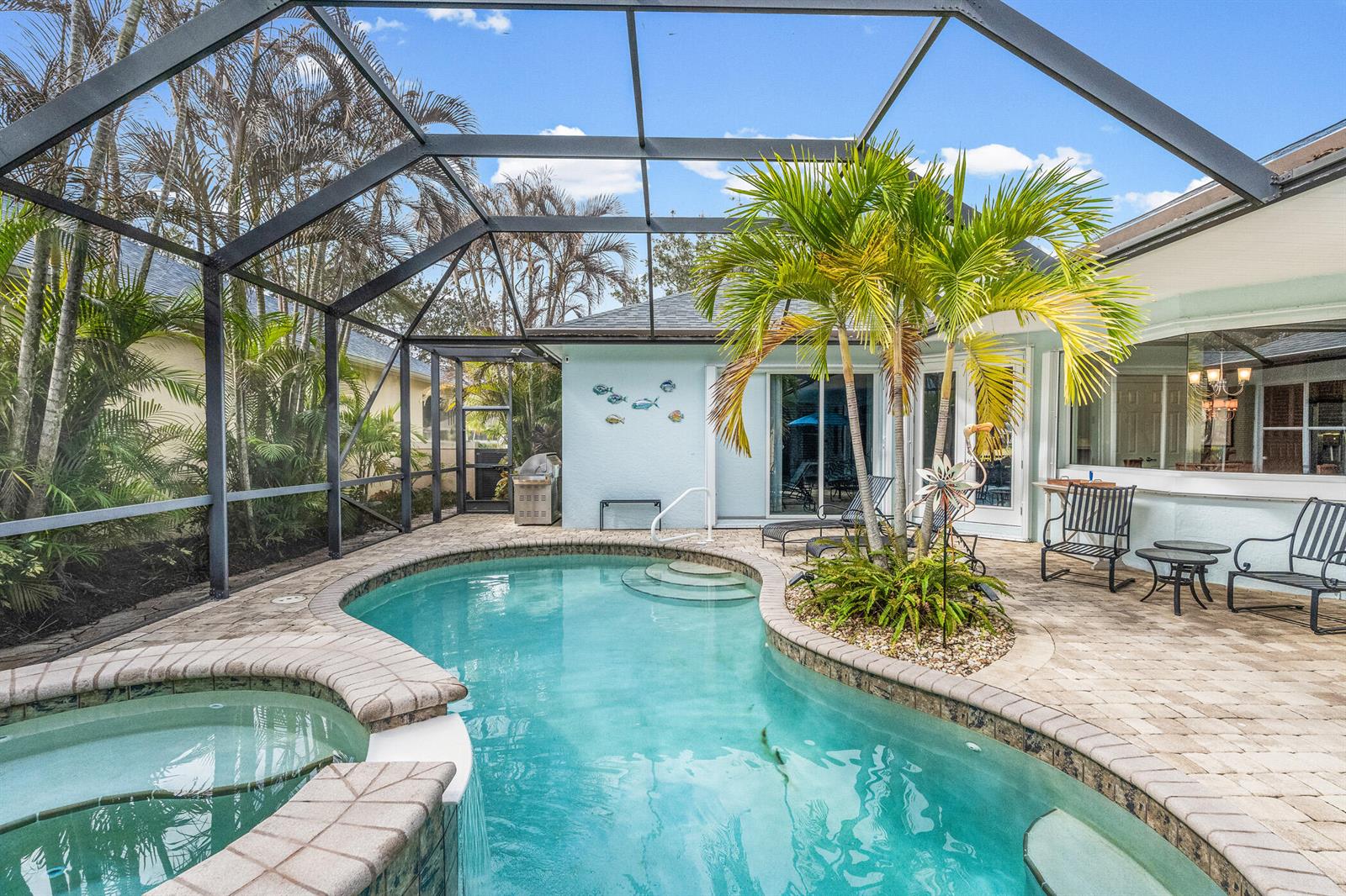 A screened-in patio features a swimming pool, a hot tub, and a central palm tree — 224 Oak Hammock Circle SW, Vero Beach FL 32962, VERO BEACH, FL