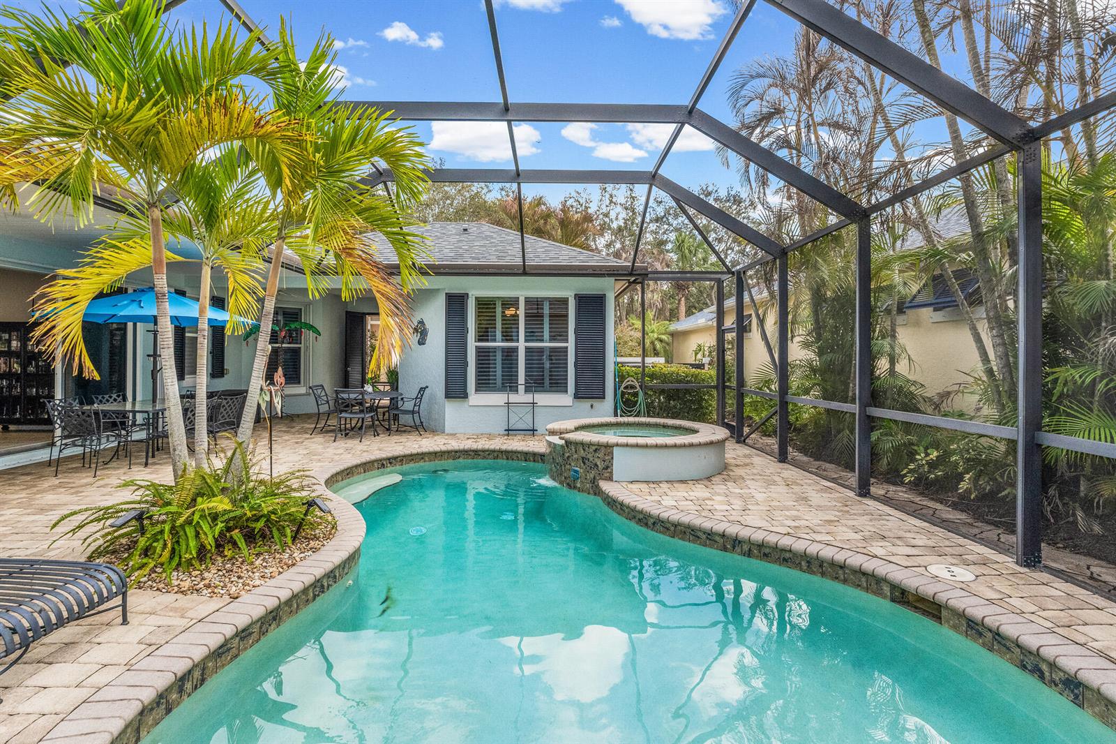 A screened-in patio features a swimming pool, a raised spa, and palm trees — 224 Oak Hammock Circle SW, Vero Beach FL 32962, VERO BEACH, FL