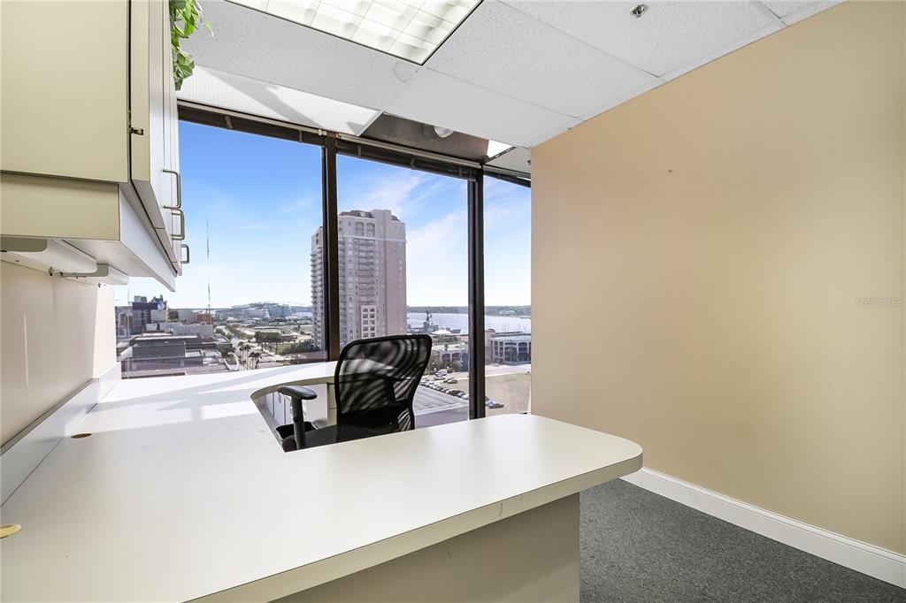 An office with a white desk, black chair, and large windows overlooking a city skyline — 233 E BAY STREET UNIT 1016, JACKSONVILLE, FL