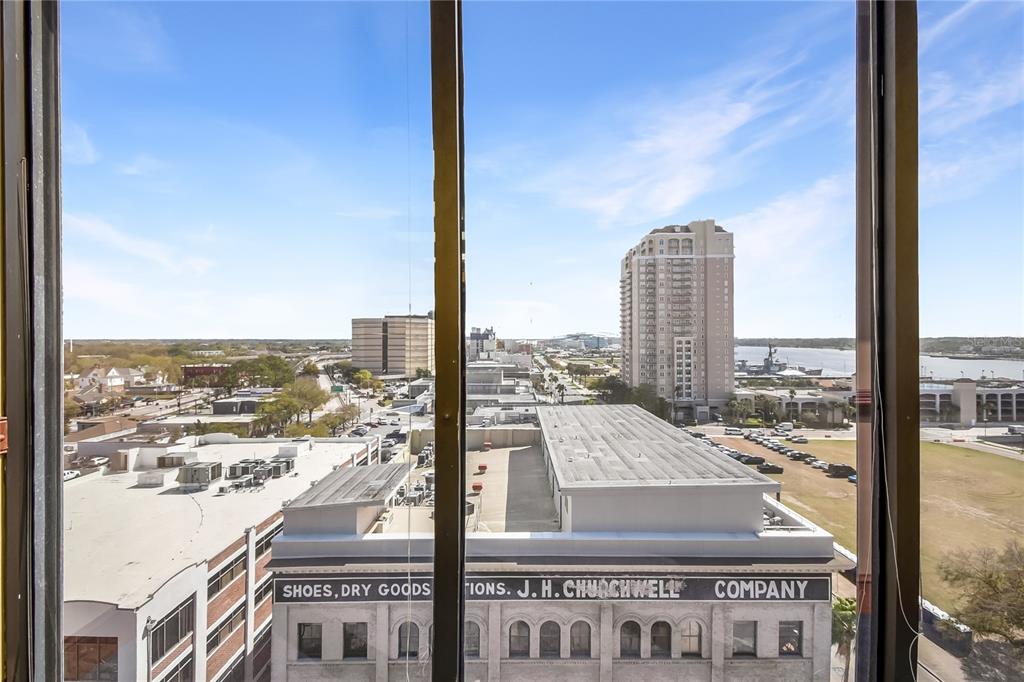 An elevated view through a window shows a city skyline and the J.H. Churchwell building — 233 E BAY STREET UNIT 1016, JACKSONVILLE, FL