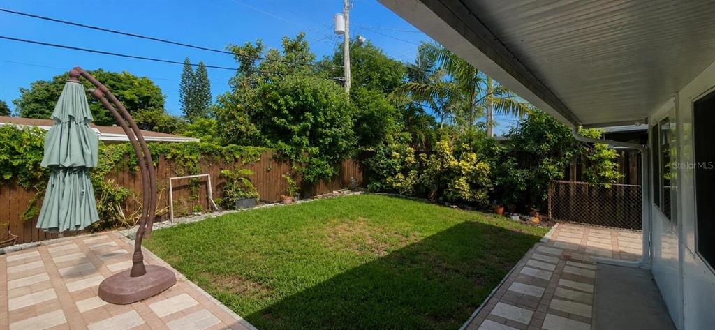 A backyard features a paved patio, a green lawn, and a wooden privacy fence — 2311 N 58TH TERRACE, HOLLYWOOD, FL