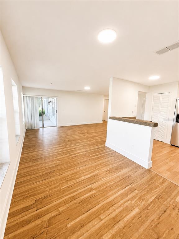 An open-concept living area features wood-look flooring, a kitchen pass-through, and sliding glass doors — 920 LOCH CARRON UNIT 16, APOPKA, FL